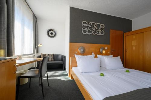 a hotel room with a bed and a desk and a room at Hotel Heymann in Kaiserslautern