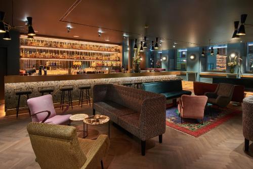 a bar with couches and chairs in a room at Hotel MIO by AMANO in Munich