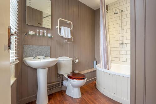 a bathroom with a toilet and a sink and a tub at The Millers Arms Inn in Canterbury