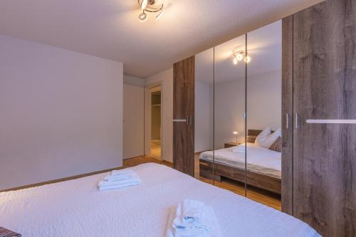 a bedroom with a white bed and a mirror at Harder Apartment - Aare Jungfrau AG in Wilderswil