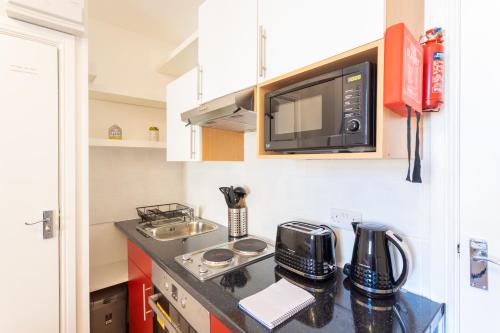 a small kitchen with a sink and a microwave at Modern 1 Bed Studio Flat in West Kilburn by Queen's Park for 2 people in London