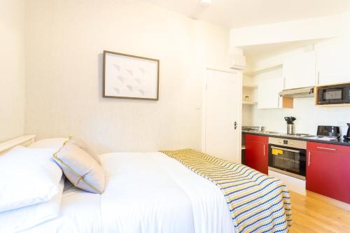 a white bed in a room with a kitchen at Modern 1 Bed Studio Flat in West Kilburn by Queen's Park for 2 people in London