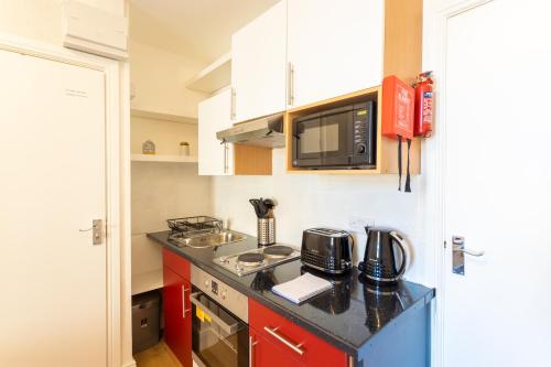 eine kleine Küche mit einer Arbeitsplatte und einer Mikrowelle in der Unterkunft Modern 1 Bed Studio Flat in West Kilburn by Queen's Park for 2 people in London