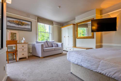 1 dormitorio con cama, sofá y TV en The Millers Arms Inn en Canterbury