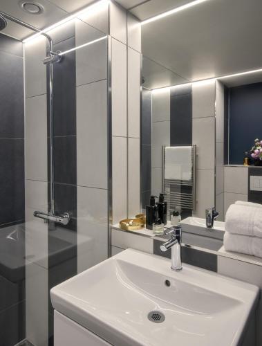 a bathroom with a sink and a shower and a mirror at Hotel MIO by AMANO in Munich