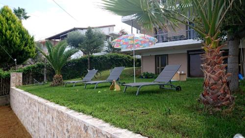a row of chairs in a yard with an umbrella at patra's sea front apartment in Flámbouras