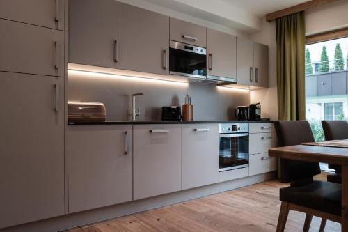 a kitchen with white cabinets and a table at Wagstätt Residenzen Jochberg by Alpina-Holiday in Jochberg