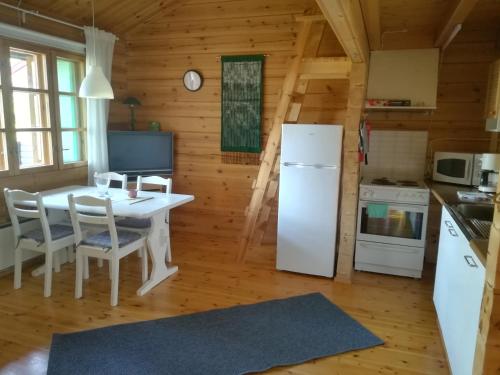 a kitchen with a table and a white refrigerator at Isotalo Farm at enäjärvi lake in Salo