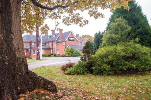 a house with a tree in front of a street at Trivelles Gatwick Hotel & airport Parking in Crawley
