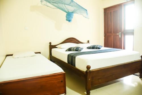 two twin beds in a room with a window at Araliya Blue Beach View Hotel in Negombo