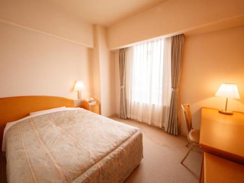 a hotel room with a bed and a window at Plaza Inn Mizusawa in Oshu