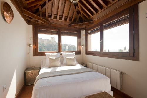 a bedroom with a large white bed with two windows at Casa Bombo in Granada