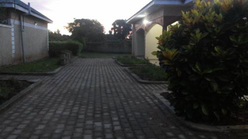 a brick walkway leading to a house with a hedge at Hotel Premier in Yumbe