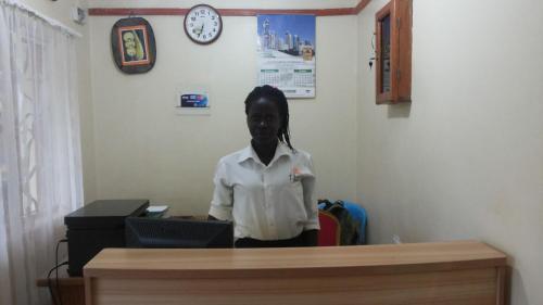 a woman standing at a desk in a room at Hotel Premier in Yumbe