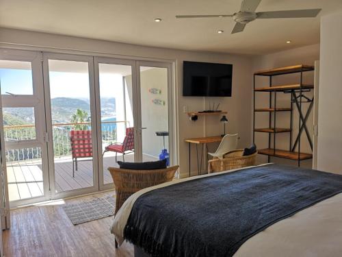 a bedroom with a large bed and a balcony at Stonebrook Apartments in Simonʼs Town