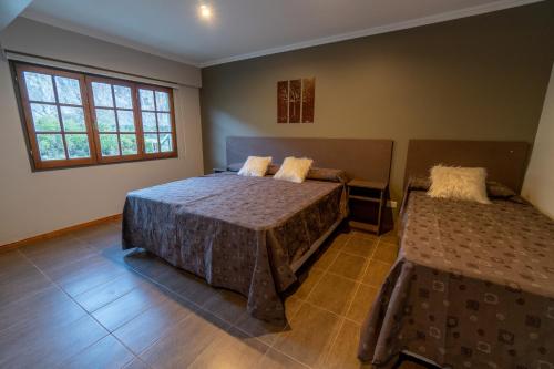 a bedroom with two beds and two windows at Fitz Roy Hostería de Montaña - El Chaltén in El Chalten