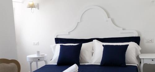 un letto bianco e blu con lenzuola e cuscini blu di Affittacamere La Cattedrale a Monopoli