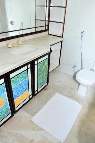 a bathroom with a sink and a toilet and windows at La Residence Flat Hotel in Goiânia