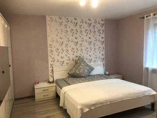 a small bedroom with a bed and a flowery wallpaper at 3 -Zimmer Wohnung im Zentrum Bad Nenndorf in Bad Nenndorf