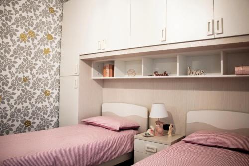 2 camas en una habitación pequeña con sábanas rosas en Res. Chalet a 10 min. da Rho Fiera e Stadio Meazza en Milán