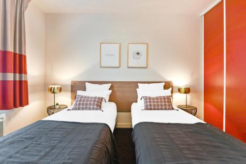 two beds in a small room with two lamps at Appart'City Confort Lille - Euralille in Lille