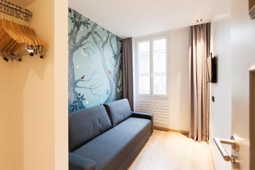 een woonkamer met een blauwe bank en een muurschildering bij Hôtel So Marais in Parijs