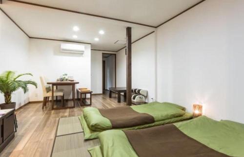 a bedroom with two green beds and a table at Funhouse Katsuragawa in Kyoto