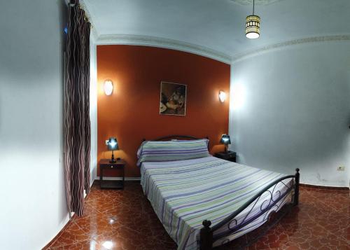 a bedroom with a large bed with an orange wall at Castillo Dalilah in Tan-Tan Plage