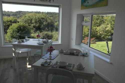 a dining room with two tables and two windows at Nettle Bank in Lyme Regis