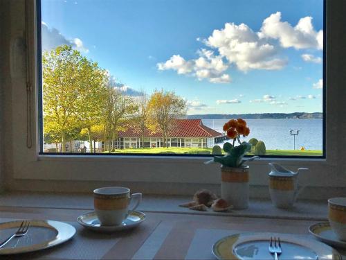 a table with a window with a view of the water at Villa Mare _Traumwohnung Gluecksbu in Glücksburg