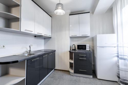 a kitchen with white cabinets and a sink and a microwave at Villa Gor Apartments in Bukovel
