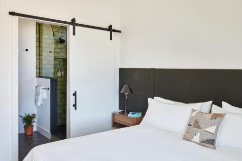 a bedroom with a white bed and a sliding door at Lokal Hotel Cape May in Cape May