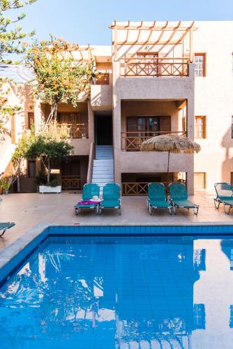 a swimming pool with chairs and a building at Anna Maria in Malia