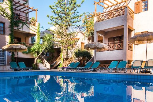 a pool at a hotel with chairs and umbrellas at Anna Maria in Malia