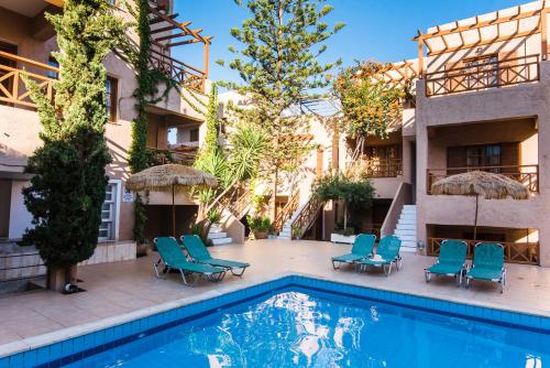 a pool with chairs and umbrellas next to a building at Anna Maria in Malia