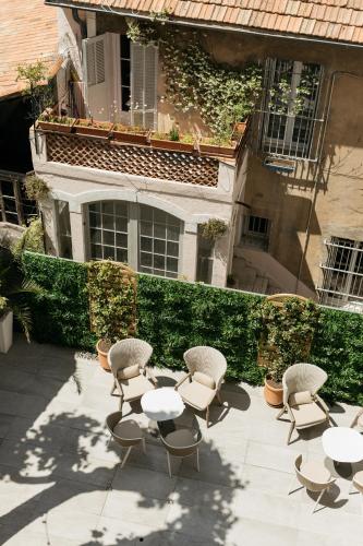 a patio with tables and chairs in front of a building at Hôtel Boutique Cézanne centre Aix-en-Provence in Aix-en-Provence