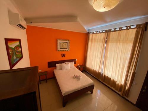 a bedroom with orange walls and a bed and a window at Hotel Doña Marta in Nicoya