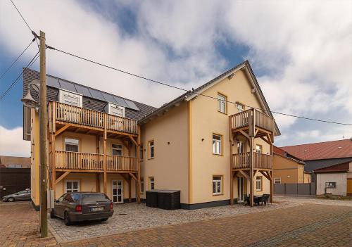 a building with balconies and a car parked in front at Gästehaus Alte Bäckerei in Dachwig
