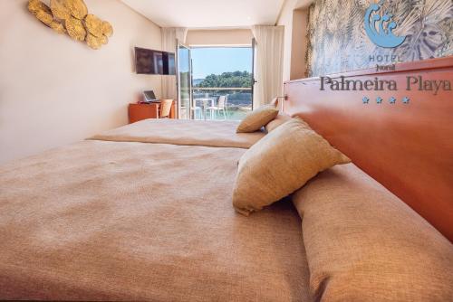 1 dormitorio con 2 camas y ventana grande en Hotel Norat Palmeira Playa, en Ribeira