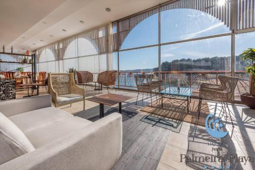 a living room with a couch and tables and windows at Hotel Norat Palmeira Playa in Ribeira