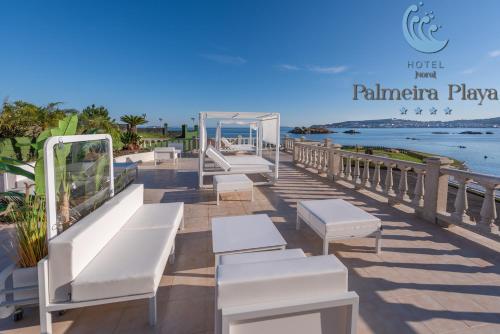 a row of white benches on a pier near the beach at Hotel Norat Palmeira Playa in Ribeira