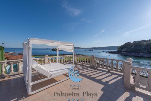 a white canopy bed on a deck overlooking the water at Hotel Norat Palmeira Playa in Ribeira