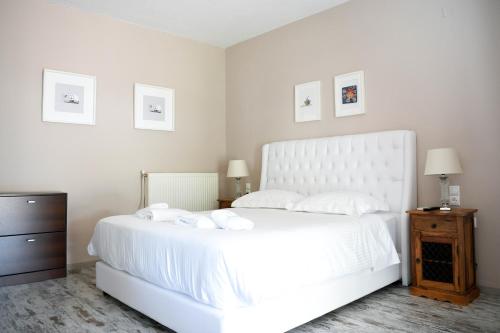 a white bedroom with a large white bed and a dresser at Serenity Luxury Villa, Skiathos in Agia Paraskevi
