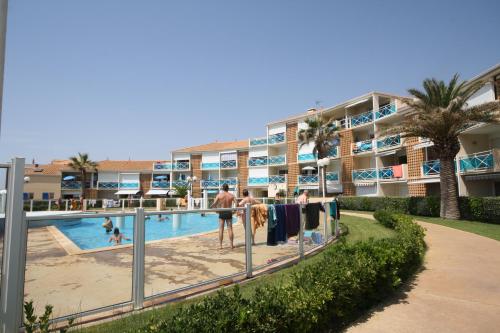 un complexe avec une piscine et des personnes séchant leurs vêtements dans l'établissement Résidence La Voile Blanche 2, à Frontignan
