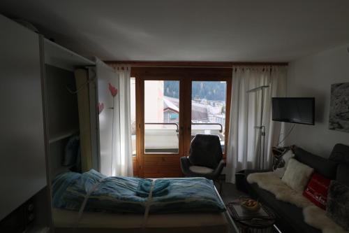 1 dormitorio con 1 cama, 1 silla y 1 ventana en Richmond - 303, en Davos