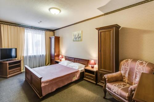 ロストフ・ナ・ドヌにあるОтель Платовскийのベッドと椅子付きのホテルルーム