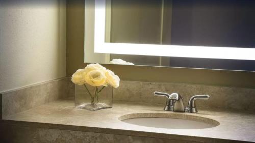 ein Waschbecken mit einer Vase mit einer gelben Rose in der Unterkunft Lakeway Resort & Spa in Lakeway