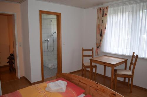 Zimmer mit einem Tisch und einem Bad mit Dusche. in der Unterkunft Hotel Restaurant Waldschlössel in Speyerbrunn