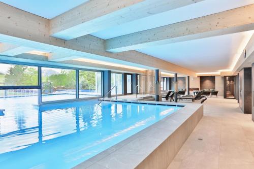 a swimming pool in a house with a large window at ERMITAGE Wellness- & Spa-Hotel in Gstaad