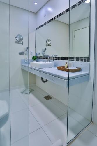 a white bathroom with a sink and a mirror at Wyndham Golden Foz Suítes in Foz do Iguaçu